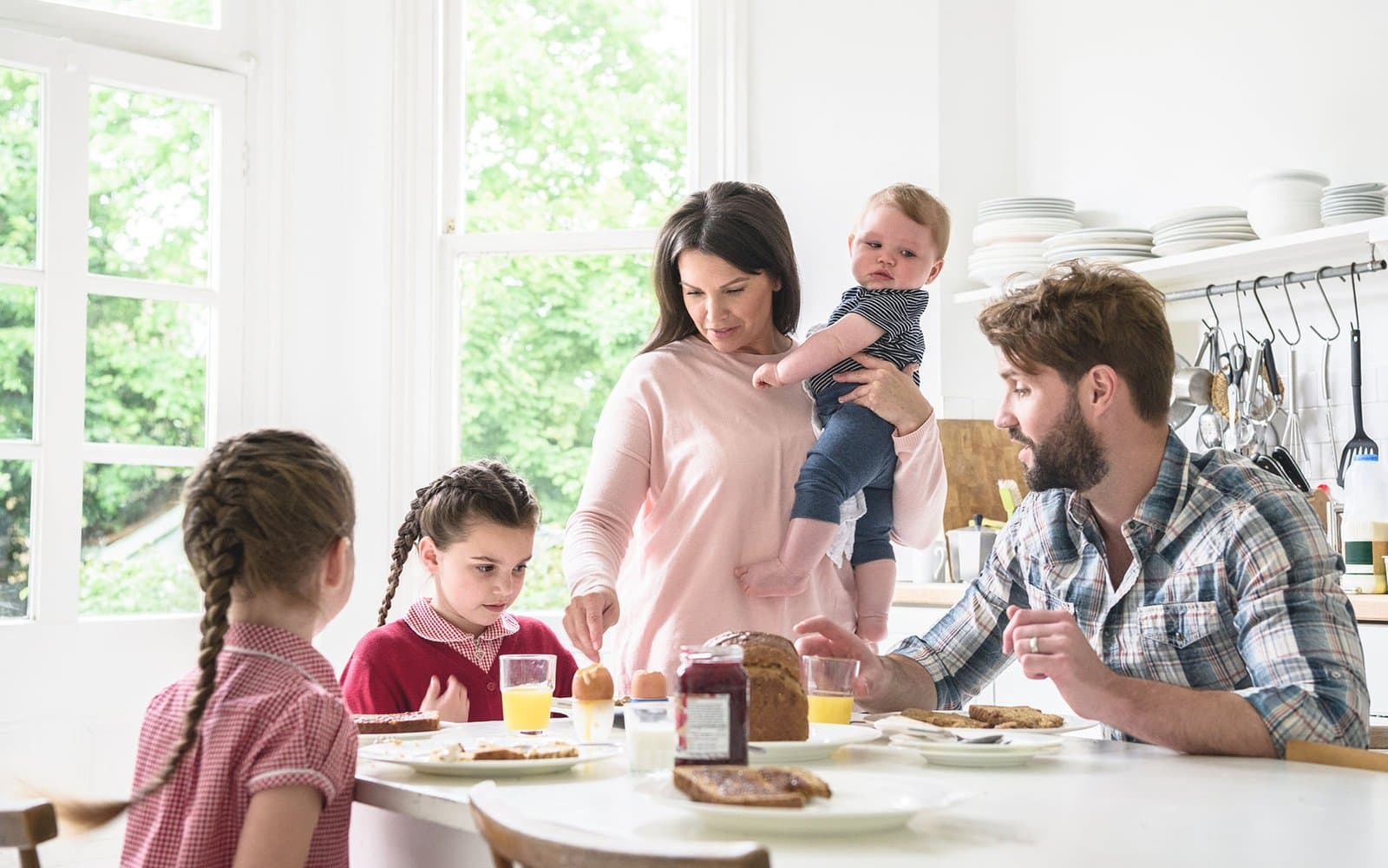 Familie mit drei Kindern beim Frühstück in der Küche