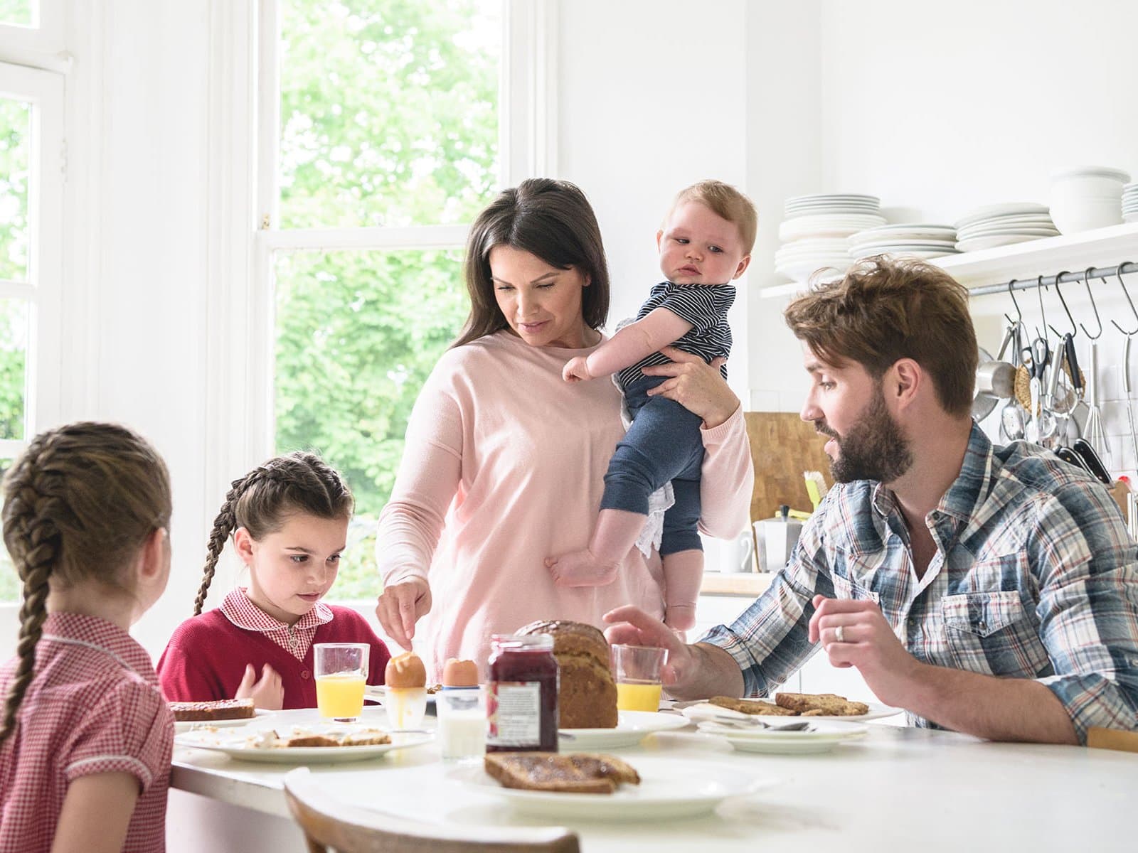 Familie mit drei Kindern beim Frühstück in der Küche