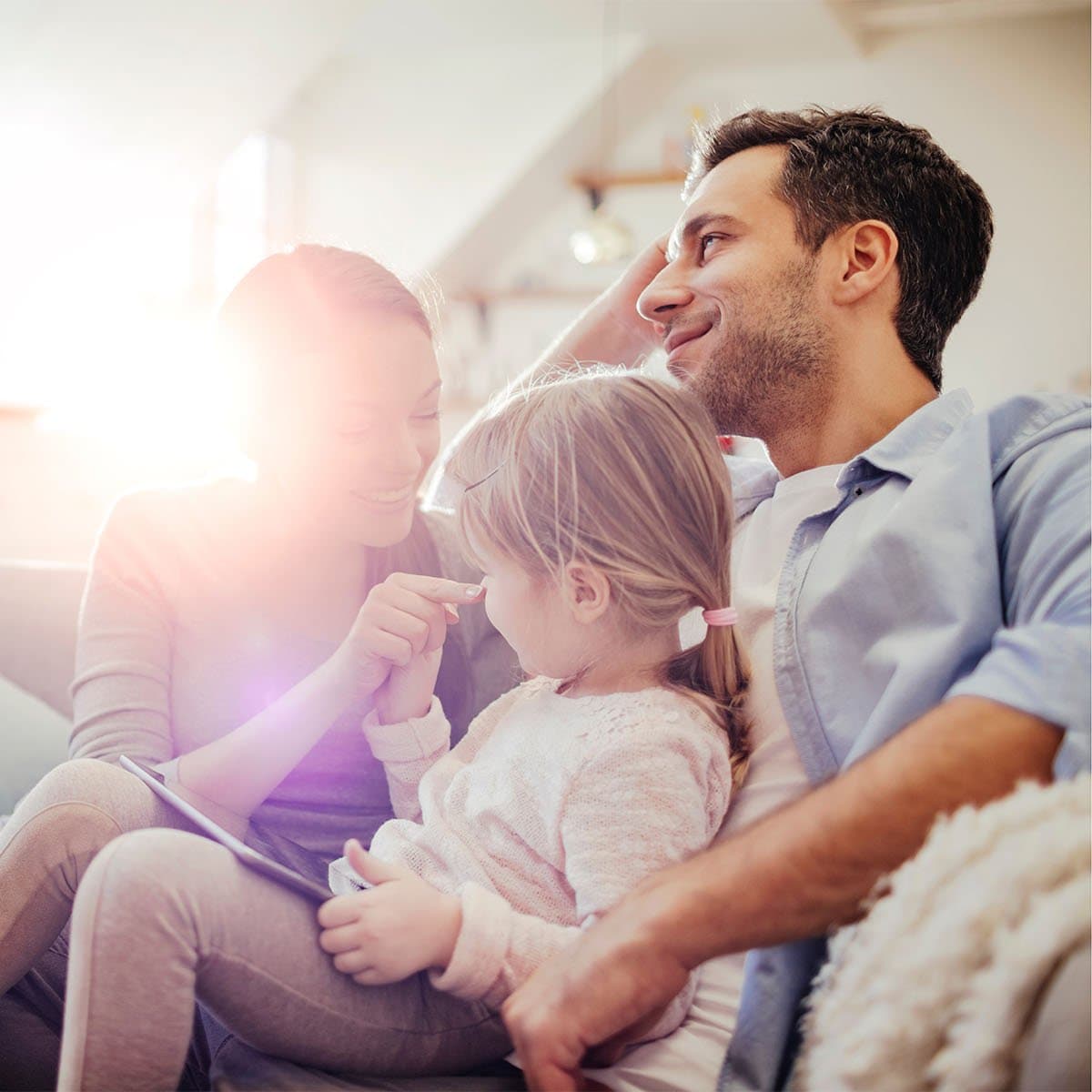 Familie sitzt entspannt zusammen auf dem Sofa im hellen Wohnzimmer