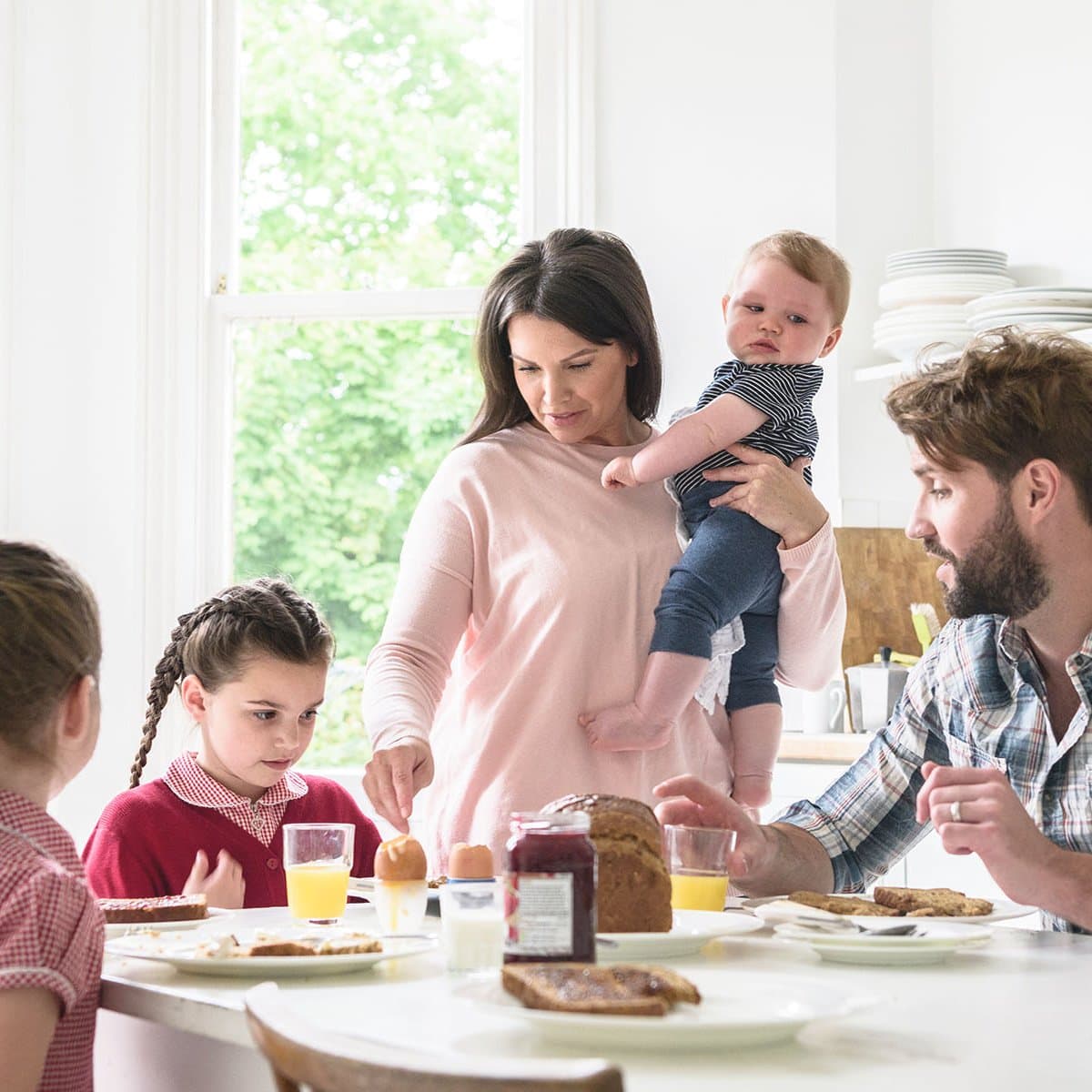 Mutter mit Baby und Kindern beim Frühstück in der Küche